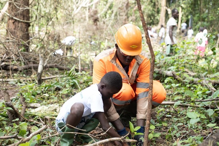 Un collaborateur et un enfant en train de planter un arbre